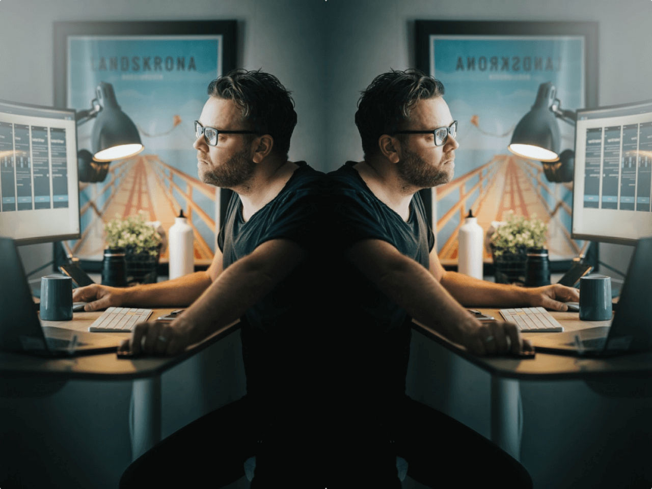 Mirrored image of man with glasses using computer at office