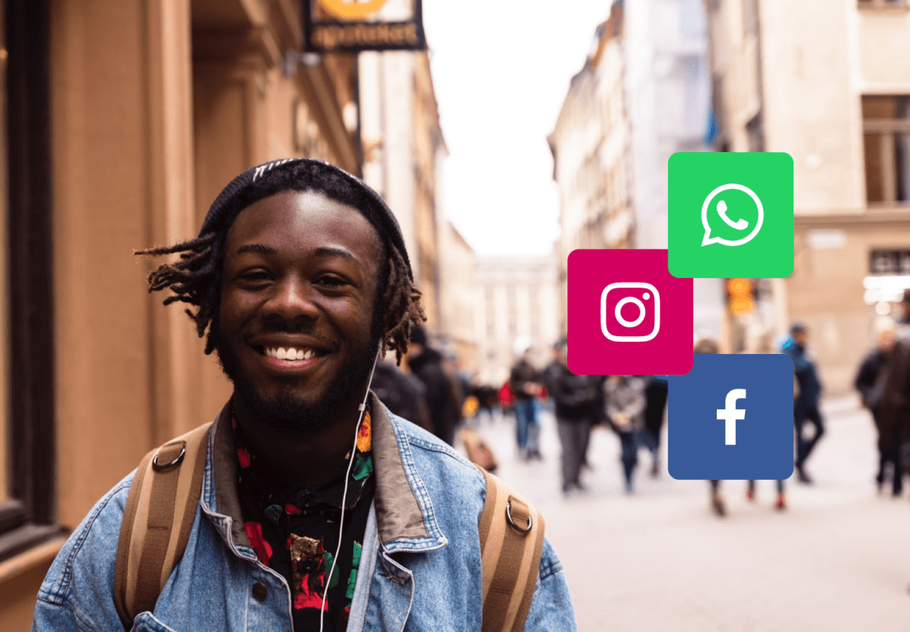 Portrait of smiling young man on the street with instagram, whatsapp and facebook logos
