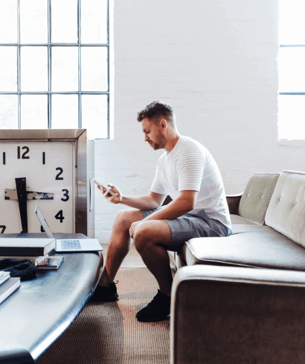 Man sitting in a couch typing chat messages on his phone